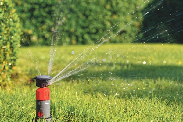 Orange automatic sprinkler in a garden while irrigation
