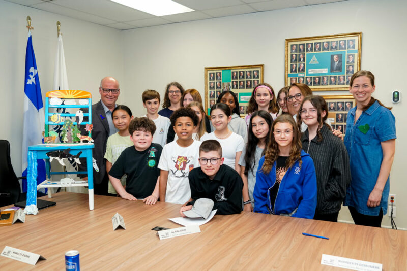 Le préfet de la MRC des Maskoutains, Simon Giard, en compagnie d’élèves de l’école Assomption et de leurs enseignantes, lors du dévoilement de la Chaise des générations. Photo François Larivière | Le Courrier ©